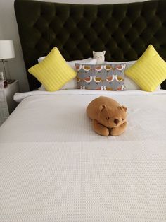 a brown teddy bear laying on top of a white bed