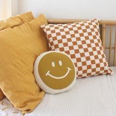 a bed topped with pillows and a smiley face pillow