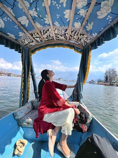 a woman sitting in the back of a boat on top of a body of water