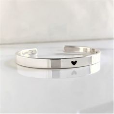 "* DETAILS:  - one .925 Solid Sterling 1/4\" x 6\", 6.5\", 7\", 7.5\" or 8\" cuff bracelet with a small heart engraved on the center - inside text, 50 characters or less - all cuffs can be adjusted with slight pressure to be made tighter or looser » DON'T FORGET TO GRAB A SUNSHINE POLISHING CLOTH: https://www.etsy.com/listing/469627127/sunshine-cleaning-cloth-for-jewelry?ref=shop_home_active_1 » CHECK OUT MY ENTIRE SHOP https://www.etsy.com/shop/TatumBradleyCo?ref=si_shop » My Shop Feedback: https://www.etsy.com/your/shops/TatumBradleyCo/reviews?ref=shop_info" Stackable Sterling Silver Bracelet For Anniversary, Sterling Silver Hand-stamped Bracelet, Minimalist Heart-shaped Promise Bracelets, Silver Hand Stamped Bangle Bracelets, Silver Hand Stamped Bangle Jewelry, Hand Stamped Silver Bangle Bracelets, Minimalist Bangle Jewelry For Valentine's Day, Adjustable Hand Stamped Sterling Silver Bracelet, Classic Heart-shaped Sterling Silver Bracelet