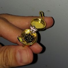 a person is holding a gold compass charm