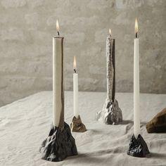 three white candles sitting next to each other on top of a table covered in snow