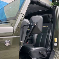 the interior of a green jeep with its doors open and seats folded down in front of it