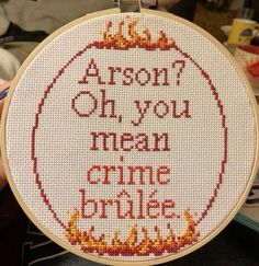 there is a cross stitch on the hoop with words written in red and orange letters