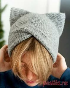 a woman wearing a gray knitted hat with a cat ears on it's head