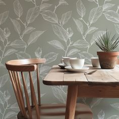 two wooden chairs sitting next to a table with cups and saucers on top of it