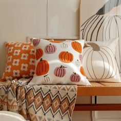 several decorative pumpkin pillows on a wooden bench