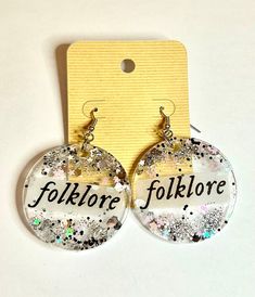 the earrings are decorated with glitter and have words that read follmore, follmore