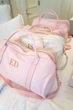 three pink and white duffel bags sitting on top of a bed