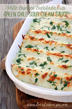 a casserole dish with cheese and spinach in it on a wooden board