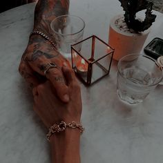 a man with tattoos on his arm holding onto a glass and another person's hand