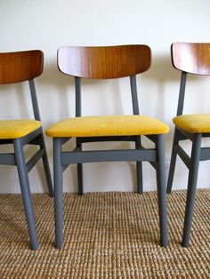 three wooden chairs sitting next to each other on top of a carpeted floor in front of a white wall