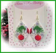 a pair of earrings with cherries hanging from it's sides on top of a card