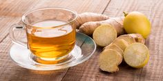 a glass cup filled with tea next to sliced lemons and ginger on a wooden table