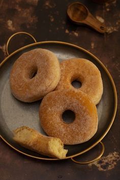 three glazed donuts on a plate with spoons