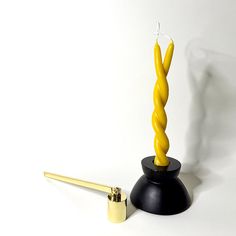 A black candle holder holding a yellow twisted candle to symbolize a twin flame with a brass candle snuffer next to it. Twisted Candle, Twist Candle, Custom Book, Band Engagement Ring, Twin Flame, Custom Engagement Ring, Candle Holder, Candle Holders, Fine Jewelry