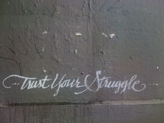 graffiti on the side of a building that says, trust your struggle with white writing