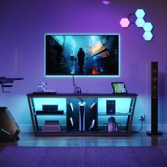 the entertainment center is lit up with purple lighting and electronics on it's sides