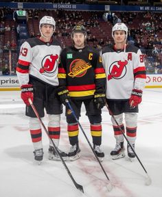 three hockey players standing on the ice in front of an arena full of people watching