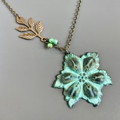 "Flower Necklace - Verdigris Patina Flower Pendant accented with an Antiqued Brass Branch and small Turquoise Czech Glass Beads. The Flower is 43 mm (a little over 1.5\") in diameter and is a stamping with a hollow back. 20\" Antiqued Brass Chain and Findings Be sure to check out my Patina Collection for similar items. http://www.etsy.com/shop/mcstoneworks?section_id=6573408" Green Bohemian Flower Charm Necklace, Green Bohemian Flower Necklace, Bohemian Green Flower Necklace, Patina Jewelry, Jewelry Flower, Jewelry Turquoise, Floral Jewelry, Botanical Jewelry, Gift For Woman