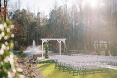 an outdoor ceremony setup with white chairs and water spouting from the back ground