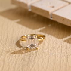 an engagement ring sitting on top of a piece of paper next to a small object