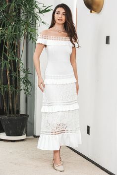 a woman standing in front of a plant wearing a white dress