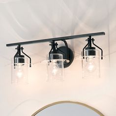 three light bathroom fixture with clear glass jars on the front and back lights above it