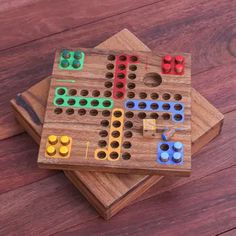 a wooden board game set on top of two coasters with colored pegs in the middle