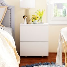 a bedroom with white furniture and yellow flowers on the nightstand next to the bed in the room