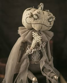 a cloth doll is dressed in white and has pearls on it's head, while wearing a veil