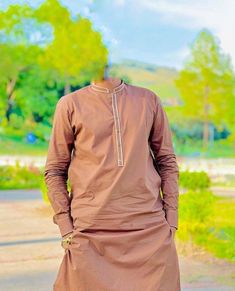 a man standing on the side of a road wearing a brown outfit