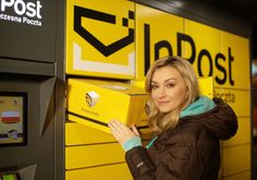 a woman standing in front of a post office vending machine with her hand on the box