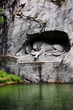 a statue of a lion in the middle of a cave next to a body of water