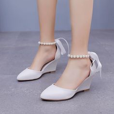 a woman wearing white shoes with pearls on the ankle