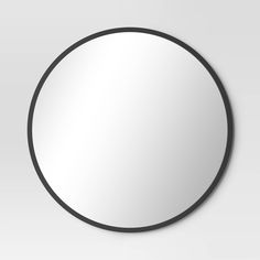 a round mirror on the wall with a black border around it and a white background