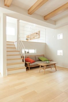 a living room with white walls and wooden floors, stairs leading up to the second floor