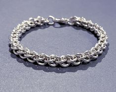 a close up of a chain bracelet on a gray surface with an empty space in the middle