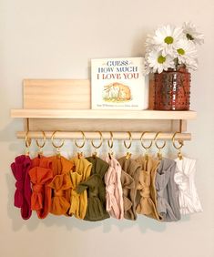 there is a rack with scarves hanging from it and a book on the shelf