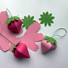 paper strawberries and leaves are arranged on a white surface