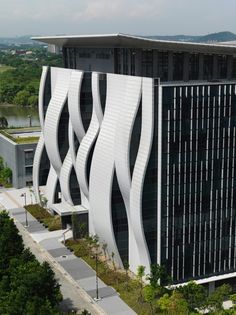 an aerial view of a modern building with wavy lines on the side and trees in front