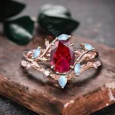 a close up of a ring with a red stone in it on a wooden surface