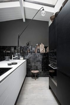 a kitchen with black and white walls and floor tiles on the wall, along with an island in the middle