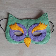 a green and purple mask with yellow eyes