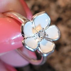 a close up of a person's hand holding a flower ring