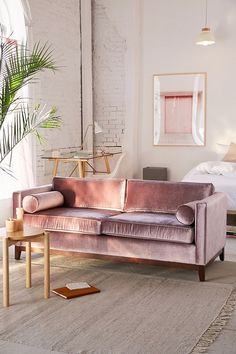 a living room with a couch, table and rug in front of a brick wall