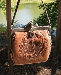 a brown purse hanging from the side of a wooden pole next to a body of water