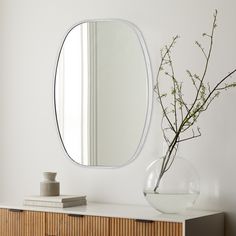 a vase filled with flowers sitting on top of a wooden dresser next to a mirror