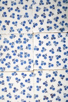 four blue and white tiles with small flowers on them, all arranged in the same pattern