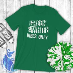 green and white vibes only t - shirt next to pair of sneakers on wooden floor